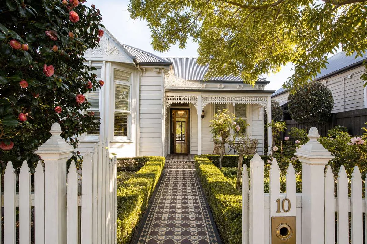 Front garden of a Melbourne heritage home with a picket fence, tessellated tile path and established period planting